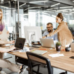 Group of diverse colleagues working on the computers in the modern office or coworking space, bearded hipster as a programmer writing code